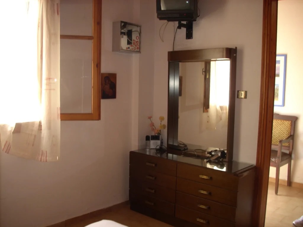 Bedroom with chest of drawers, mirror and TV