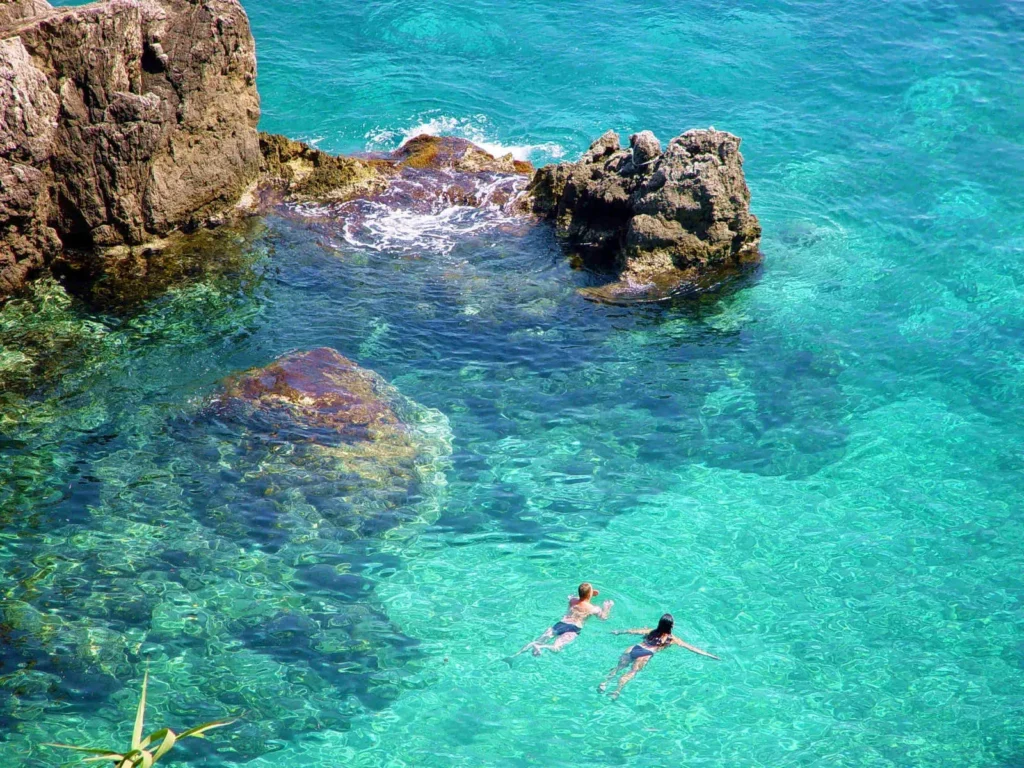 Swimmers in turquoise water among the rocks, Ithaca